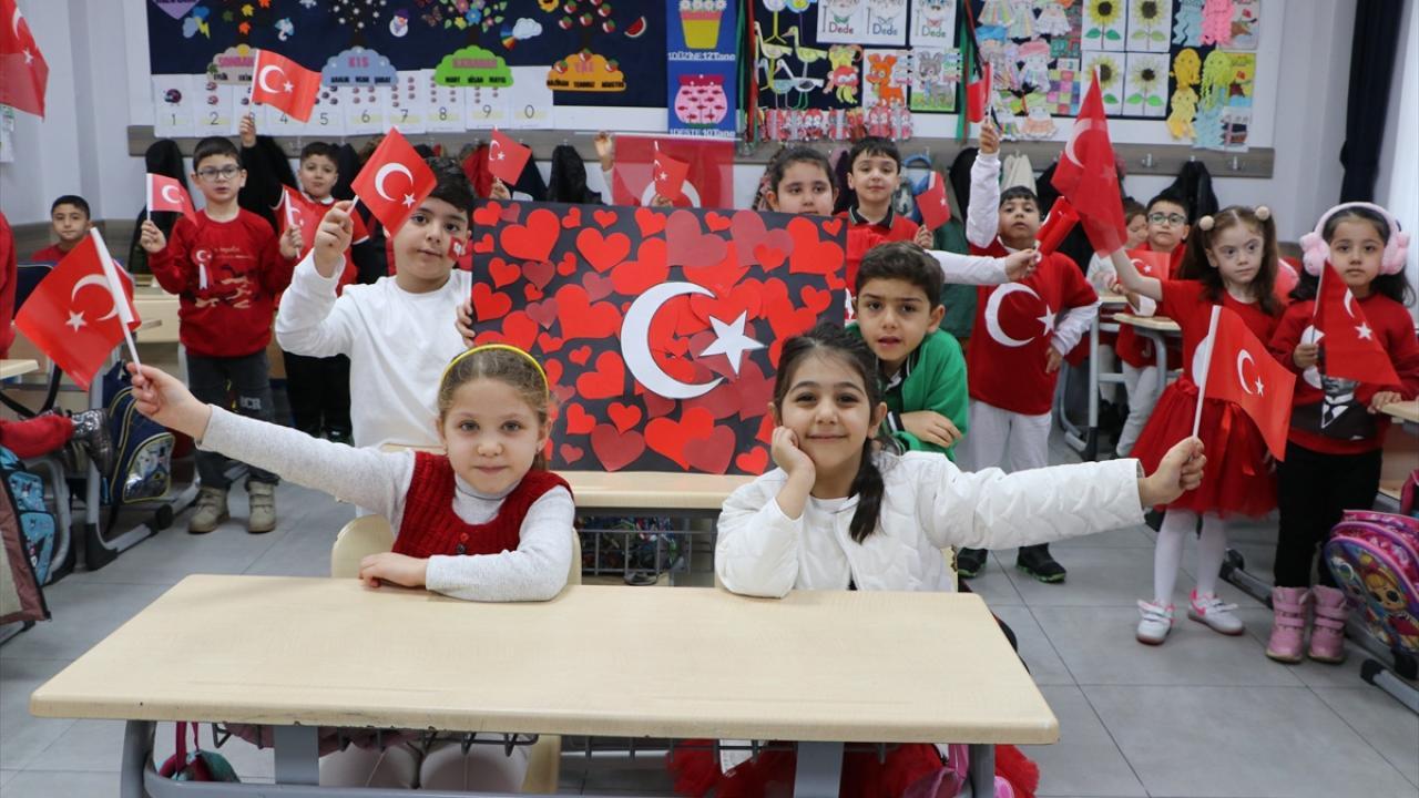 Sınıfta kendi yaptıkları kartondan Türk Bayrağını ve küçük bayrakları tutan öğrenciler